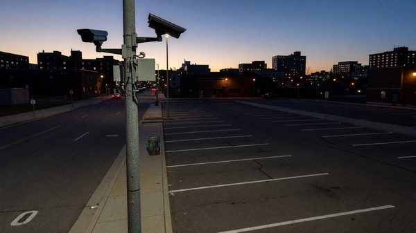 Overhead-mounted curbside camera sensor monitoring an on-street parking and loading zone in a downtown commercial district