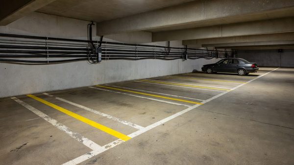 Underground parking garage with marked stalls and electrical conduit along the wall