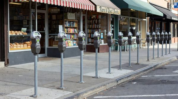 Urban street parking meters with city buildings in background representing demand-based pricing zones