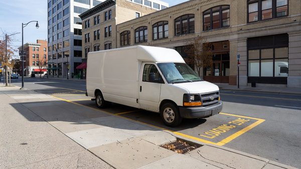 Commercial delivery van parked at a marked urban curb loading zone