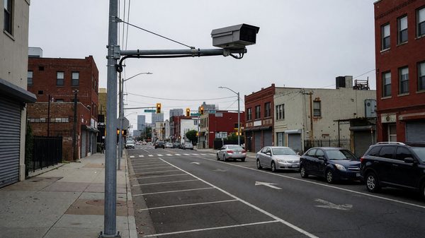 City street with license plate reader camera mounted on infrastructure above a parking lane